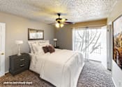 Thumbnail 4 of 25 - A bedroom with a bed, nightstand, and a ceiling fan.