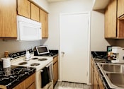 Thumbnail 7 of 25 - A kitchen with a stove, microwave, and sink.