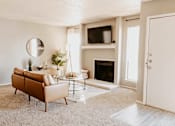 Thumbnail 1 of 25 - A living room with a brown sofa, a fireplace, and a mirror on the wall.