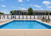 Thumbnail 14 of 20 - A swimming pool surrounded by a white fence and chairs.
