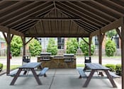 Thumbnail 22 of 27 - A wooden pavilion with picnic tables and grills.