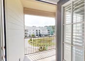Thumbnail 7 of 27 - A balcony with a view of a green lawn and a row of houses.