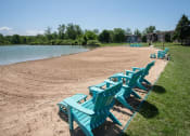 Thumbnail 13 of 23 - a row of blue beach chairs sitting on the sand near a lake