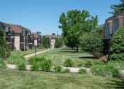 Thumbnail 22 of 23 - a yard with grass and trees in front of apartment buildings