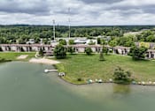 Thumbnail 31 of 32 - A large building complex sits on a grassy area next to a body of water.