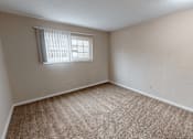 Thumbnail 8 of 32 - A room with a carpeted floor and a window with blinds.