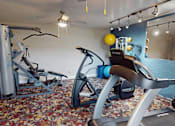 Thumbnail 14 of 32 - A gym with a variety of equipment including a leg press machine, a rowing machine, and a stationary bike.