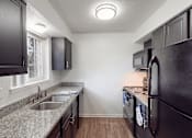 Thumbnail 2 of 32 - A kitchen with black cabinets and a granite countertop.