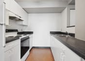 Thumbnail 21 of 29 - a kitchen with white cabinets and black counter tops
