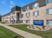Thumbnail 21 of 25 - a large brick building with a lake crest apartments sign in front of it