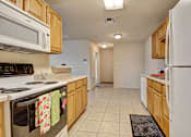 Thumbnail 1 of 30 - A kitchen with white appliances and wooden cabinets.