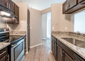 Thumbnail 3 of 35 - A kitchen with dark wood cabinets and granite countertops.