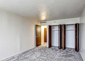 Thumbnail 14 of 24 - A room with a carpeted floor and a white ceiling with three doors.