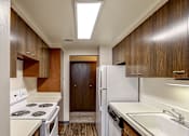 Thumbnail 3 of 24 - A kitchen with white appliances and wooden cabinets.
