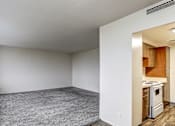 Thumbnail 10 of 24 - A kitchen area is visible through an open door in a white room.