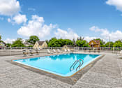 Thumbnail 23 of 24 - A large outdoor swimming pool surrounded by a fence and lounge chairs.