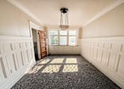 Thumbnail 20 of 32 - A room with white walls and a carpeted floor with a chandelier hanging from the ceiling.