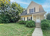 Thumbnail 17 of 32 - A house with a white door and windows surrounded by greenery.