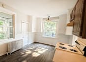 Thumbnail 23 of 32 - A sunny room with a stove and a window.