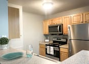 Thumbnail 5 of 18 - A kitchen with a stove, microwave, and refrigerator.