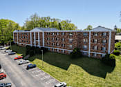 Thumbnail 25 of 25 - A large brick building with a parking lot in front.