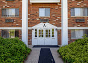 Thumbnail 22 of 25 - A brick building with a white door and a black mat in front.