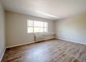 Thumbnail 6 of 25 - A room with wooden flooring and a window with blinds.