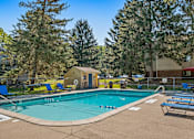 Thumbnail 13 of 18 - A swimming pool surrounded by trees and chairs.