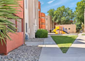 Thumbnail 16 of 18 - a sidewalk leading to an apartment building with a yellow slide in the background