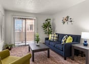 Thumbnail 5 of 25 - A living room with a blue couch, a yellow chair, and a wooden coffee table.