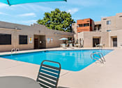 Thumbnail 21 of 25 - A pool with a chair and a building in the background.