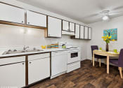 Thumbnail 3 of 12 - a kitchen with white cabinets and a dining room table