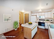 Thumbnail 2 of 6 - A kitchen with a white fridge and wooden cabinets.