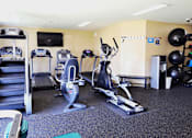 Thumbnail 10 of 18 - A gym with a variety of equipment including treadmills, exercise bikes, and weights.