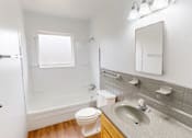 Thumbnail 11 of 16 - A white toilet sits next to a sink in a bathroom.