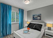 Thumbnail 9 of 25 - a bedroom with a white bed and blue curtains