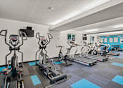 Thumbnail 14 of 25 - a gym with cardio machines and weights on a checkered floor