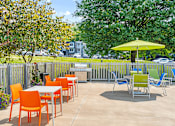 Thumbnail 20 of 25 - a patio with tables and chairs and a yellow umbrella