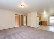 Thumbnail 7 of 32 - an empty living room with a kitchen in the background