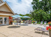 Thumbnail 11 of 21 - Sun deck patio with tables and chairs under umbrellas at apartment complex