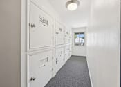 Thumbnail 22 of 34 - A hallway with storage lockers and a grey carpet.