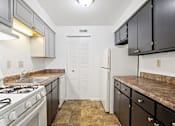 Thumbnail 7 of 34 - A kitchen with a white refrigerator and black cabinets.