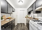 Thumbnail 3 of 34 - A kitchen with black cabinets and a white stove top oven.