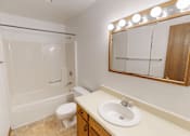 Thumbnail 6 of 35 - A bathroom with a toilet, sink, and mirror.