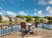 Thumbnail 27 of 35 - A table with chairs is on a deck overlooking a body of water.