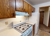 Thumbnail 9 of 35 - A kitchen with a white stove top oven and wooden cabinets.