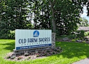 Thumbnail 29 of 35 - A sign for Old Farm Shores Apartments is displayed in a grassy area.