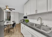 Thumbnail 4 of 26 - a kitchen with white cabinets and a sink and a table with chairs