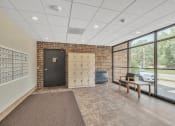 Thumbnail 17 of 26 - a lockers room with a desk and a chair in a building with large windows