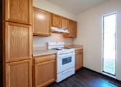 Thumbnail 2 of 20 - A kitchen with wooden cabinets and a white stove top oven.